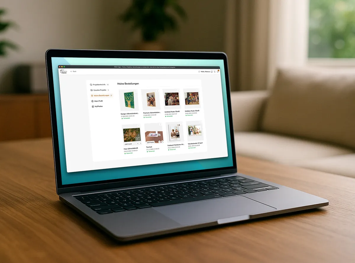 Laptop steht auf einem dunklen Holztisch und zeigt eine Übersicht von Fotoprodukt-Projekten innerhalb eines Kundenkontos